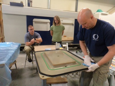 YRS students Vladimir Kevreshan and Asa Leighton watch as Jeff Reber of Composites One prepares a mold for infusion